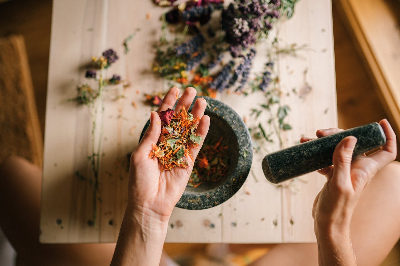 Hands grinding dried herbs with a mortar and pestle, perfect for holistic medicine and aromatherapy.